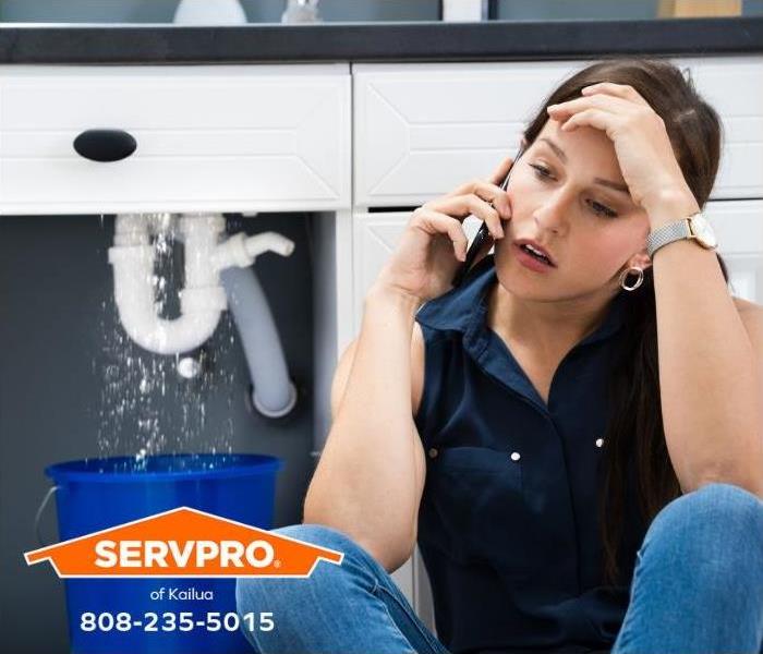 A person with a water damage emergency calls for help on their cell phone.