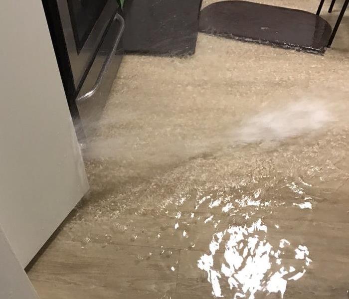 Water rushing from kitchen appliance flooding kitchen floor.