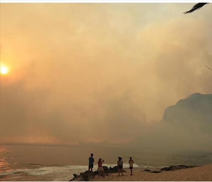 brush fire blowing thick smoke onto beach